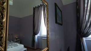 A bedroom with a bed, nightstand, and a large mirror. - Augustus Room (Roma)