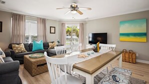 Een woonkamer met een bank, salontafel, eettafel en een televisie.
