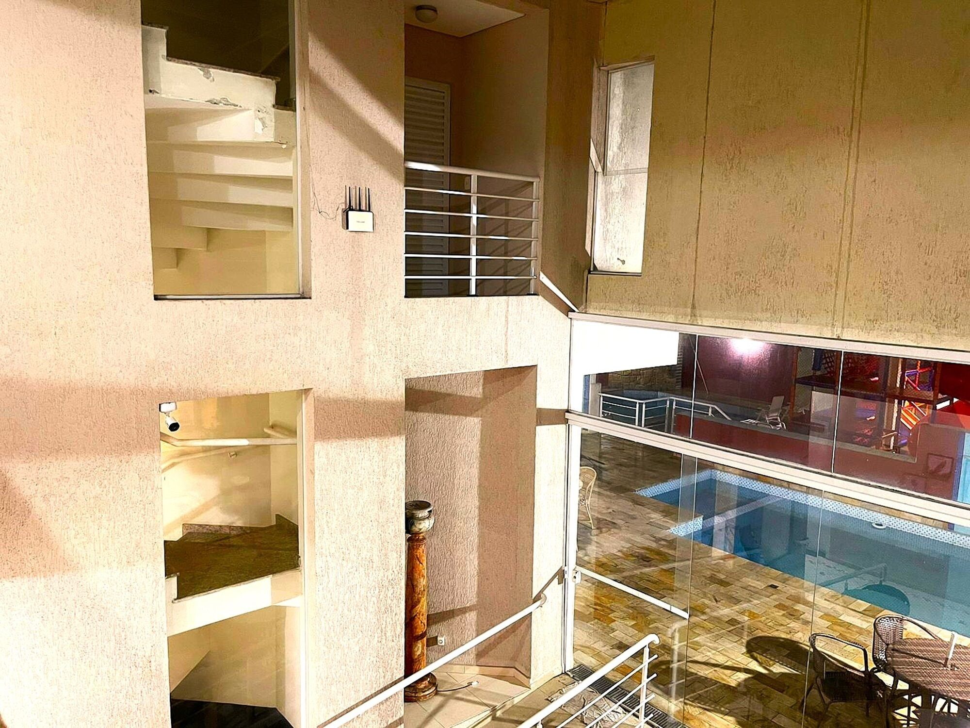 A multi-level building with a glass-bottomed pool, outdoor seating, and a staircase.