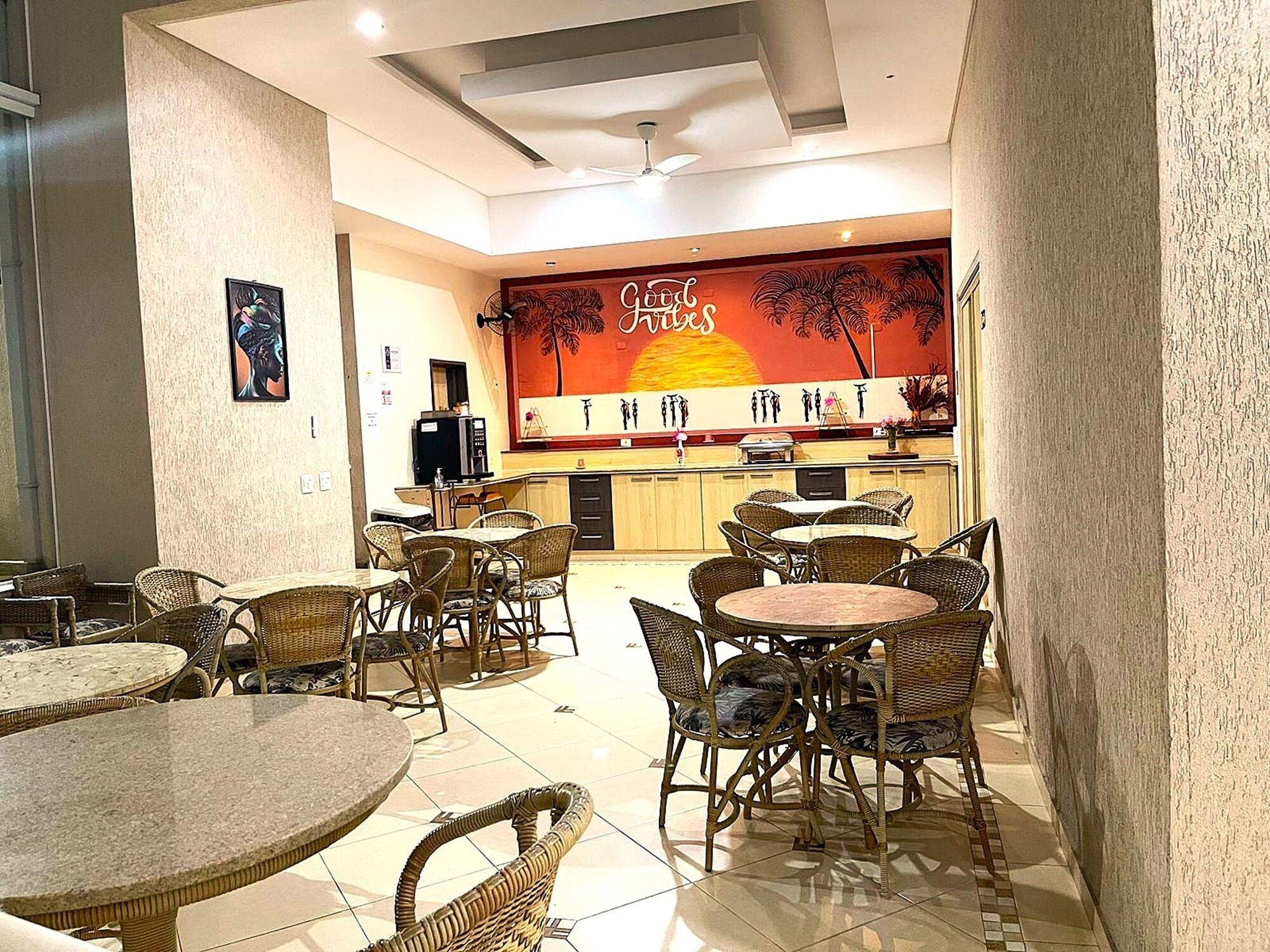 A restaurant with wicker furniture and a mural of a sunset.