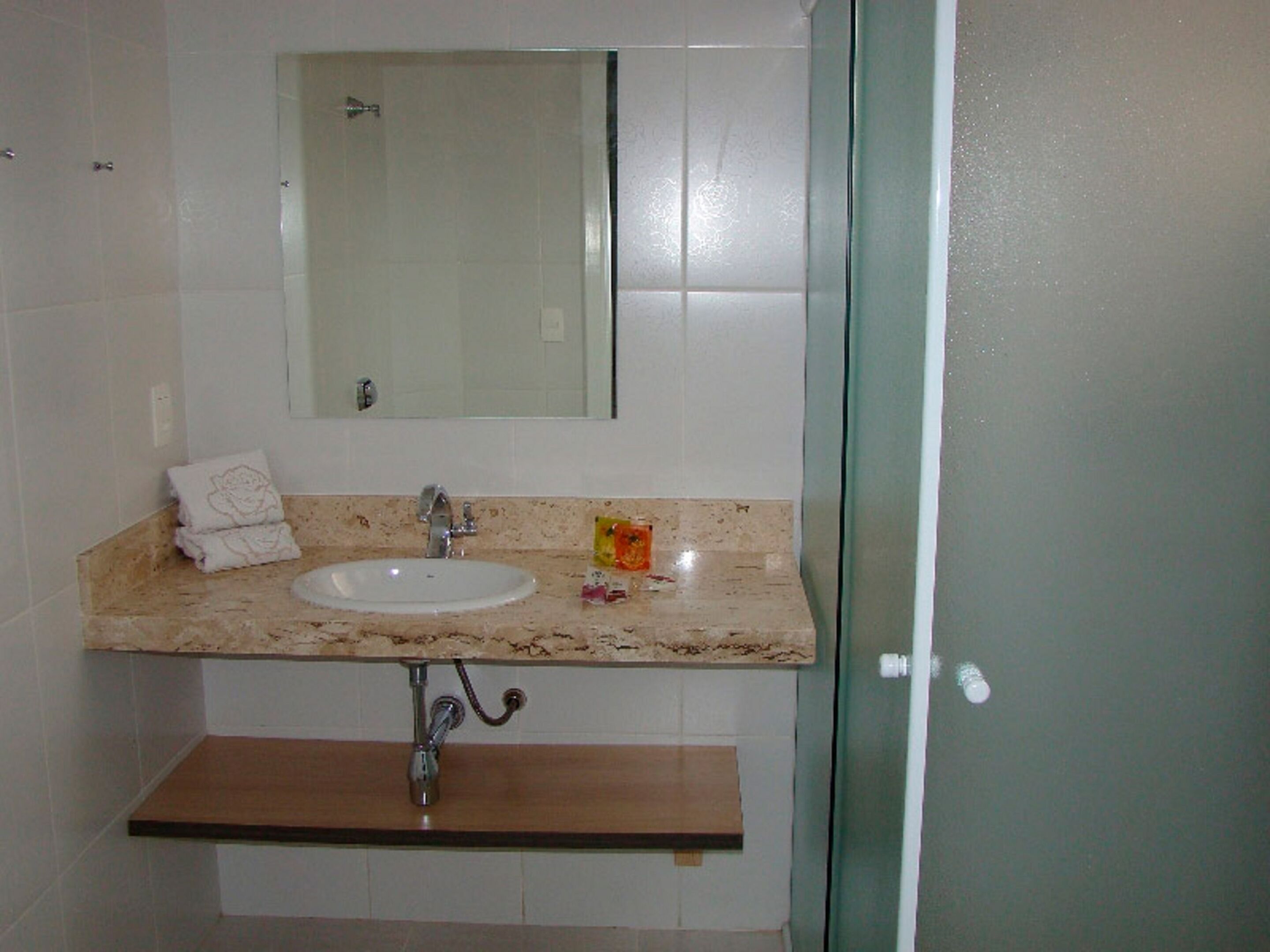 Un baño con lavabo, espejo y perchero para toallas.