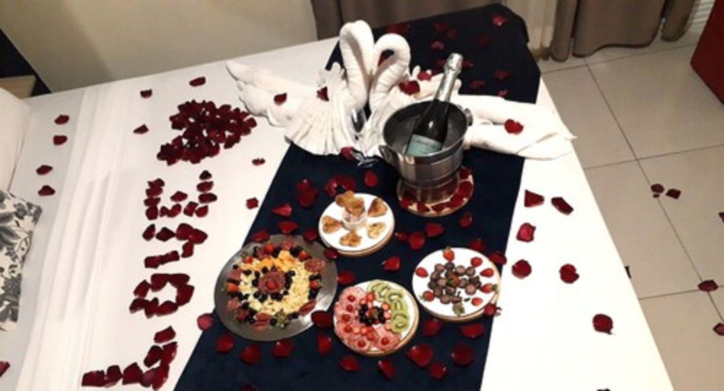 A table set with a variety of dishes, a bottle of champagne, and a decorative swan centerpiece.
