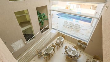 A balcony with wicker furniture, a pool, and a view of the pool area.