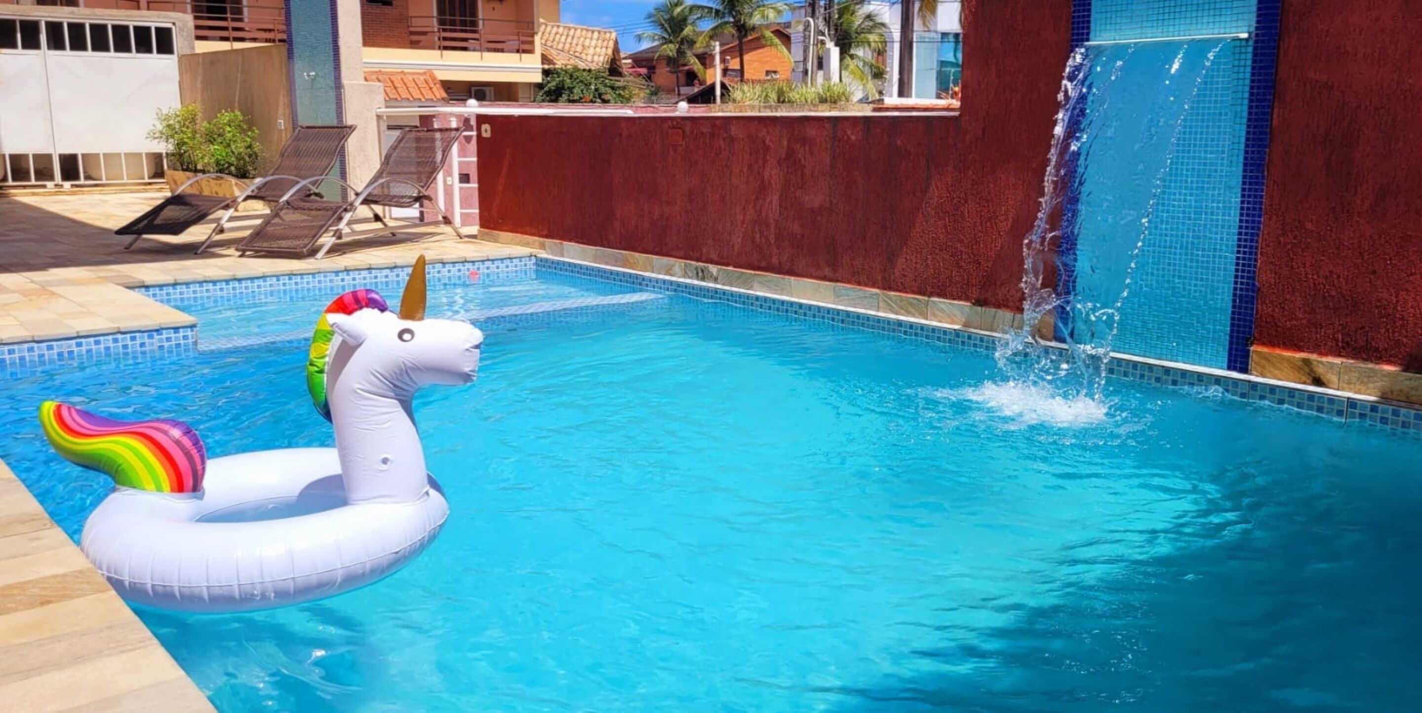 Una piscina con un flotador de unicornio y una fuente de agua.