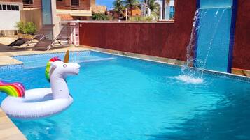 Una piscina con un flotador de unicornio y una fuente de agua.