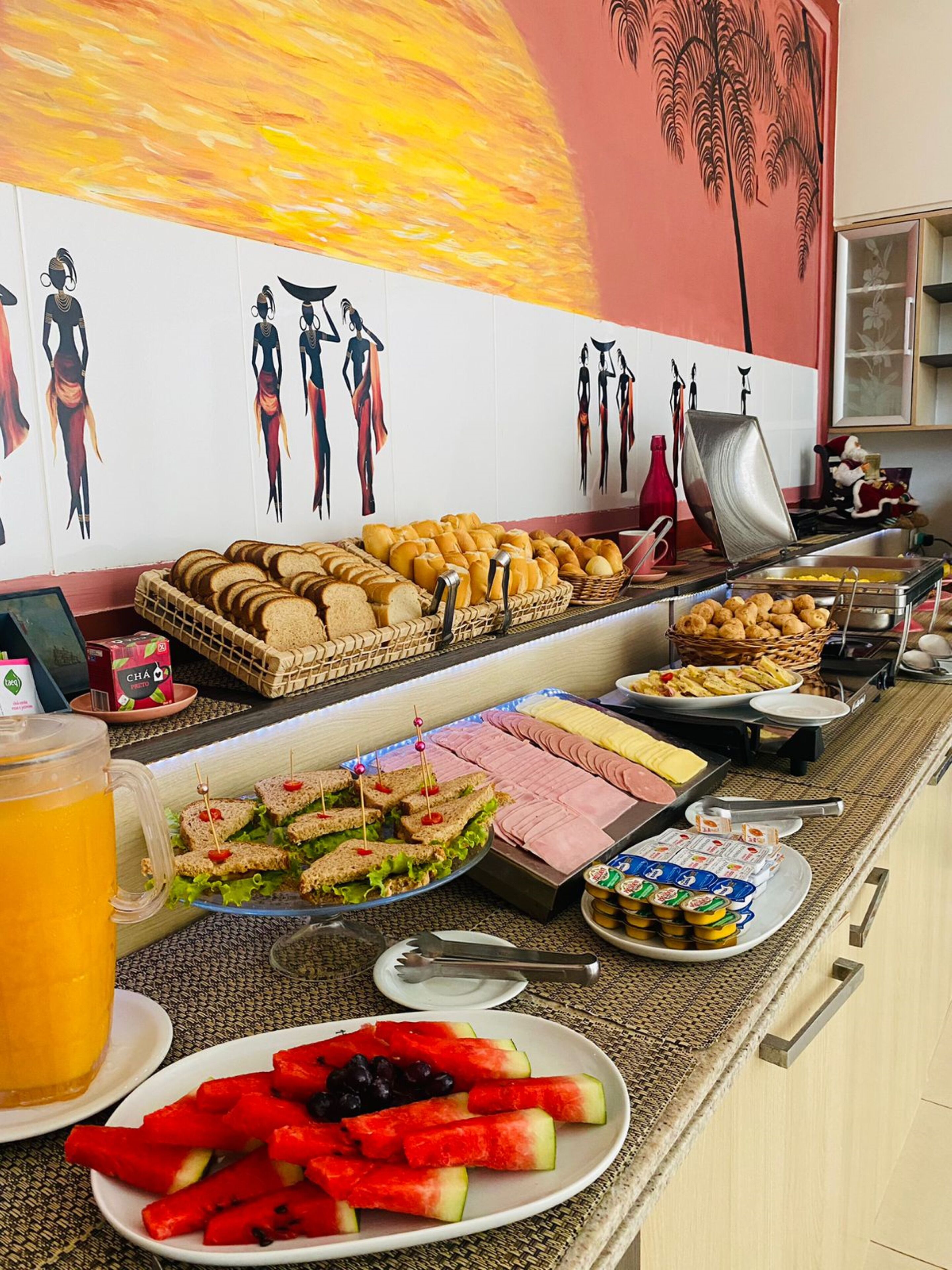A buffet with various food items including sandwiches, fruits, and beverages.