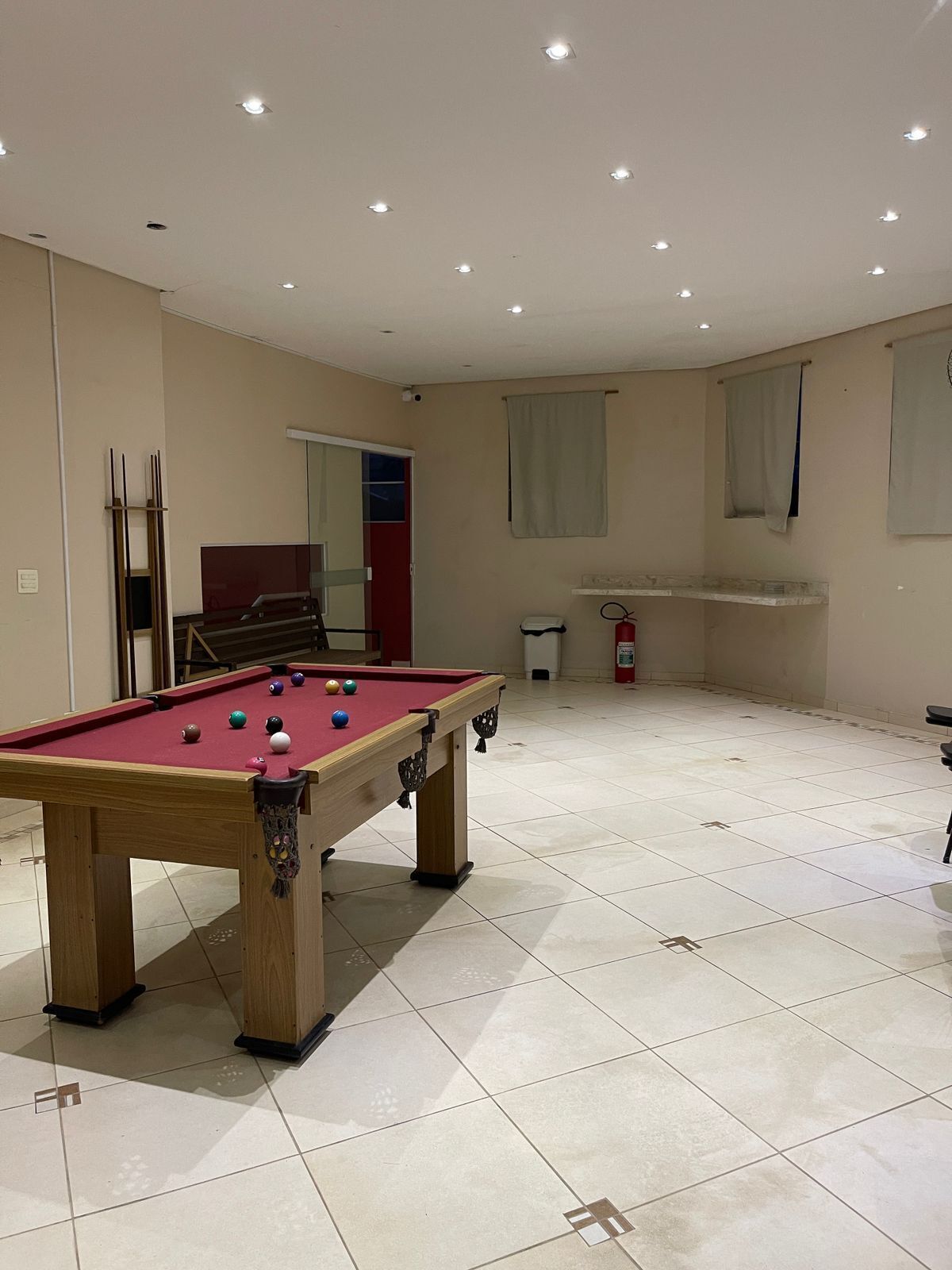 Een pooltafel in een ruimte met betegelde vloer, een brandblusser en een deur naar een andere kamer.