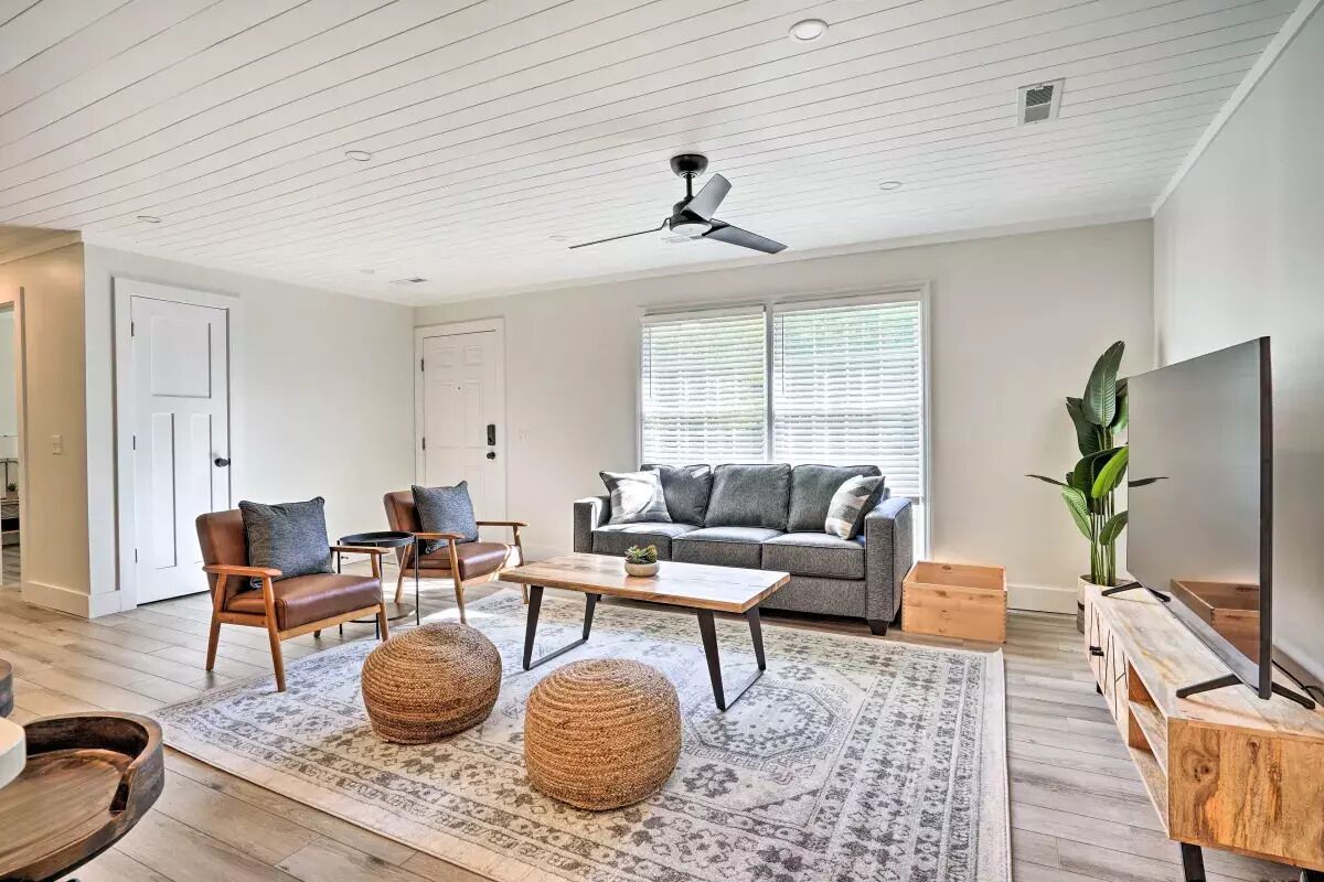A modern living room with a sofa, chairs, a coffee table, and a TV.