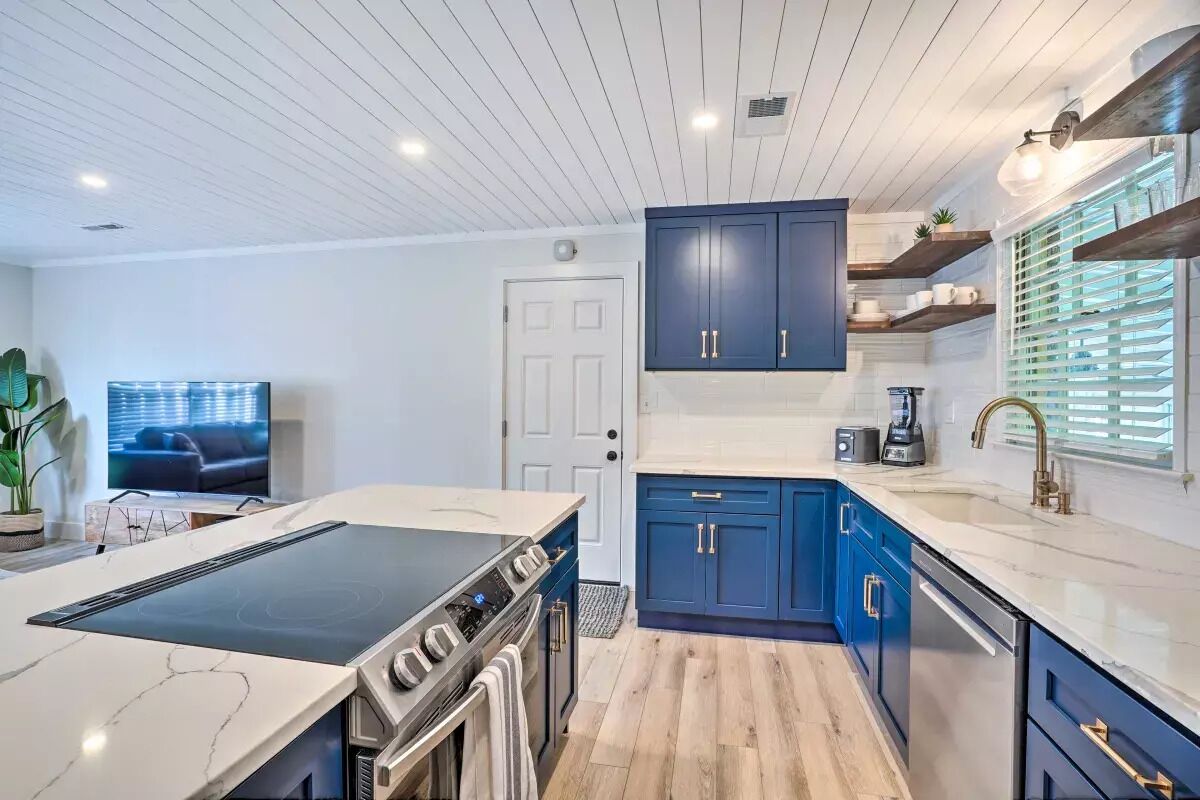 Eine moderne Küche mit Kochinsel, blauen Schränken und einem eingebauten Backofen.