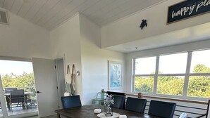 Uma área de jantar espaçosa com uma grande mesa de madeira, cadeiras azuis e um banco.