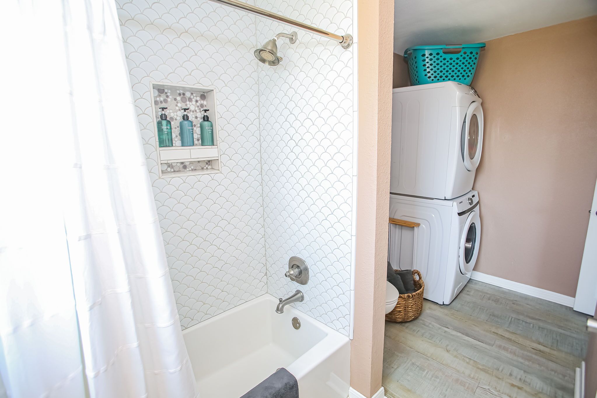 A bathroom with a bathtub, a shower, and a washing machine.