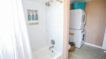 A bathroom with a bathtub, a shower, and a washing machine.
