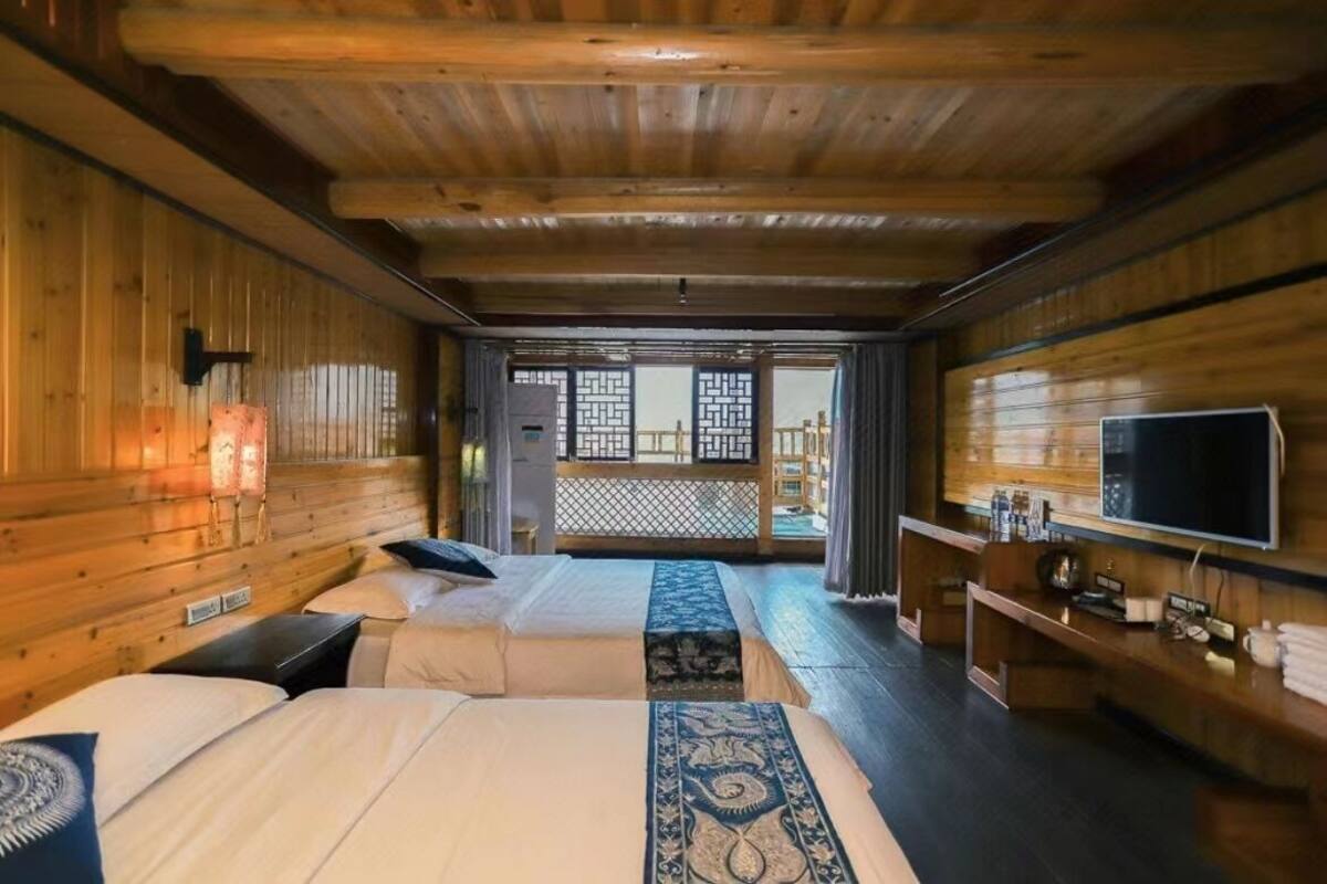 Een houten kamer met twee bedden, een televisie en een klein tafeltje.