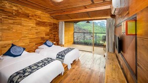 Une chambre avec deux lits, des murs en bois, un balcon avec vue et un téléviseur fixé au mur.
