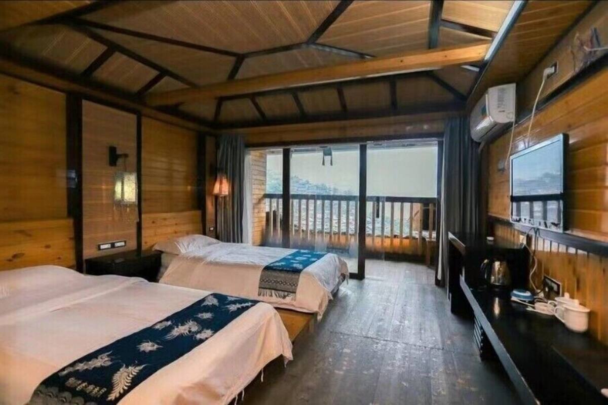 Een chalet met twee bedden, een houten interieur, een balkon met een leuning en een koffieapparaat op een aanrecht.