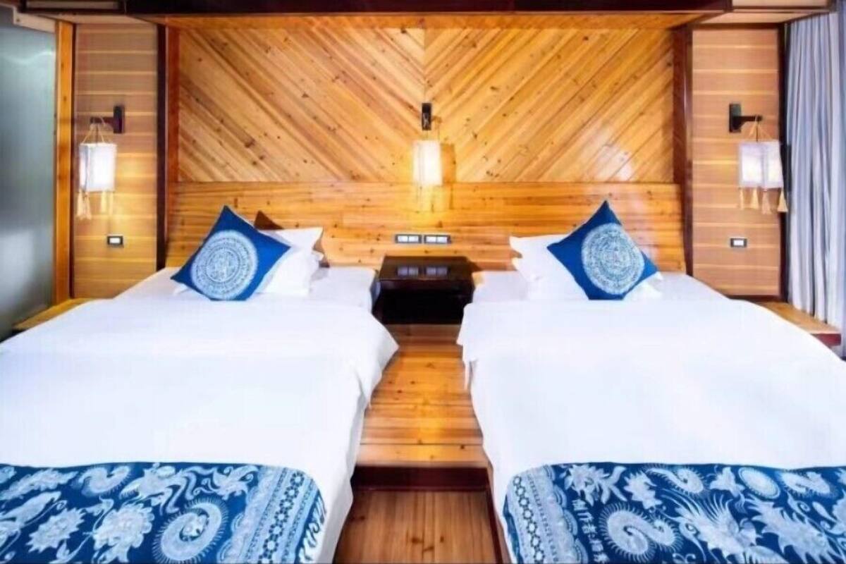 Een tweepersoonskamer met houten lambrisering en twee bedden met bijpassend blauw-wit beddengoed.