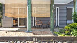 A covered patio with two chairs and a table, a sliding glass door, and a rock garden. - Urban Apartment in the Heart of Paddington (Paddington)