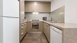 A compact kitchen with a built-in oven, microwave, and dishwasher. - Gorgeous 3-Bed Apartment Near Flagstaff Gardens (West Melbourne)