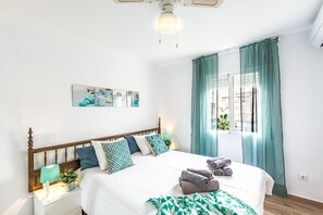 A neatly made bed with pillows, a bedside lamp, and a window with curtains.