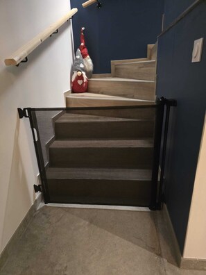 A staircase with a mesh safety gate, a red gnome decoration, and a wooden handrail. - Villa Lion | Private Spa, Pool/Jacuzzi, Terrace, Arcade (Ittenheim)