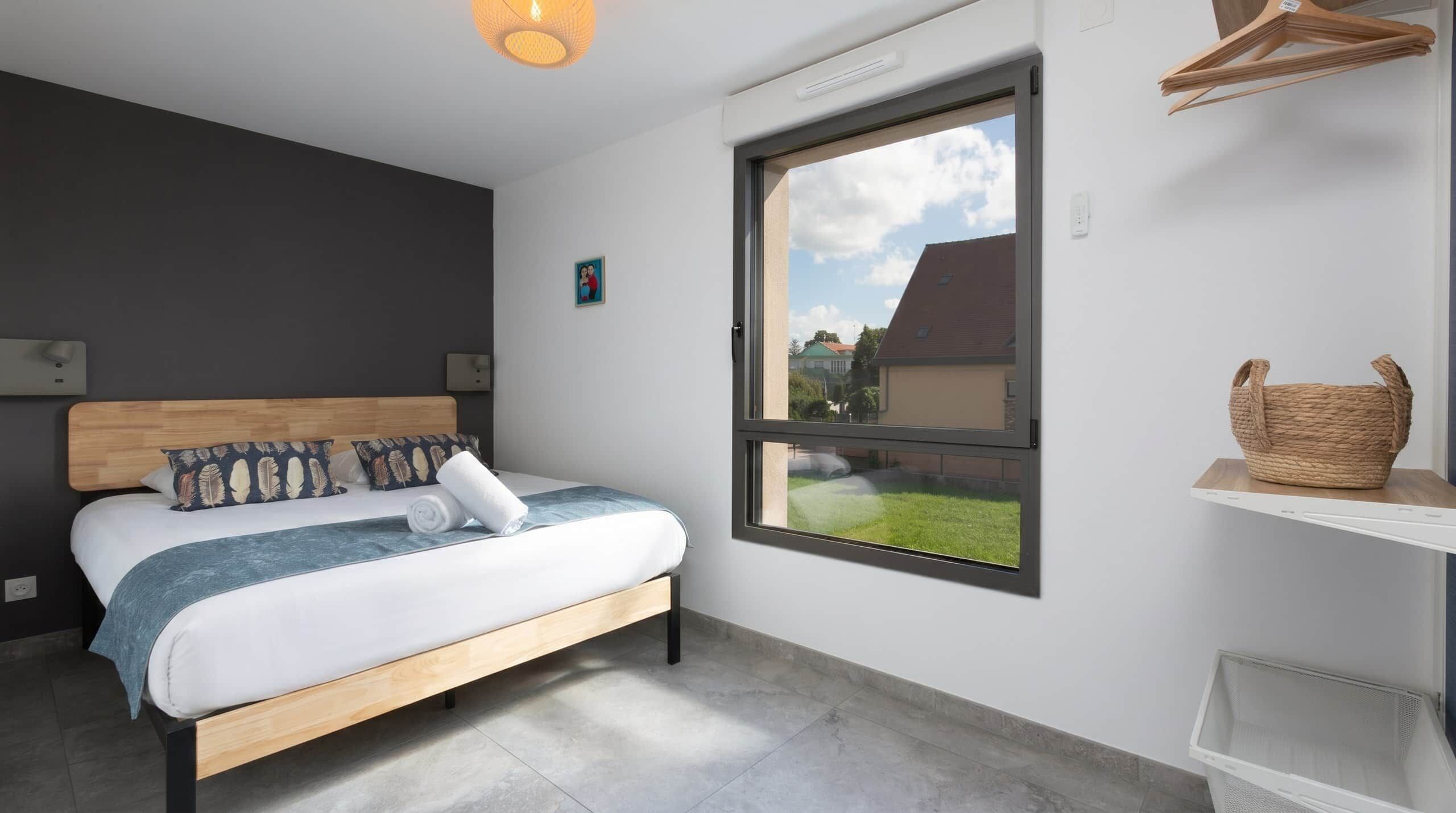 A modern bedroom with a bed, a window, and a view of the outside.
