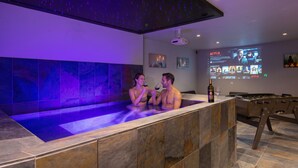A modern spa area with a heated pool, a foosball table, and a Netflix screen in the background. - Villa Lion | Private Spa, Pool/Jacuzzi, Terrace, Arcade (Ittenheim)