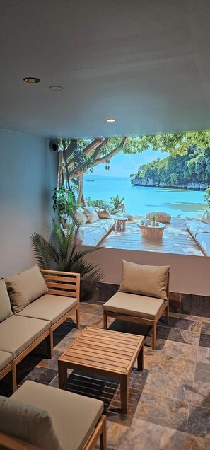 A sunlit outdoor seating area with a view of a tropical beach and clear blue sky. - Villa Lion | Private spa, pool/hot tub, terrace, game room (Ittenheim)