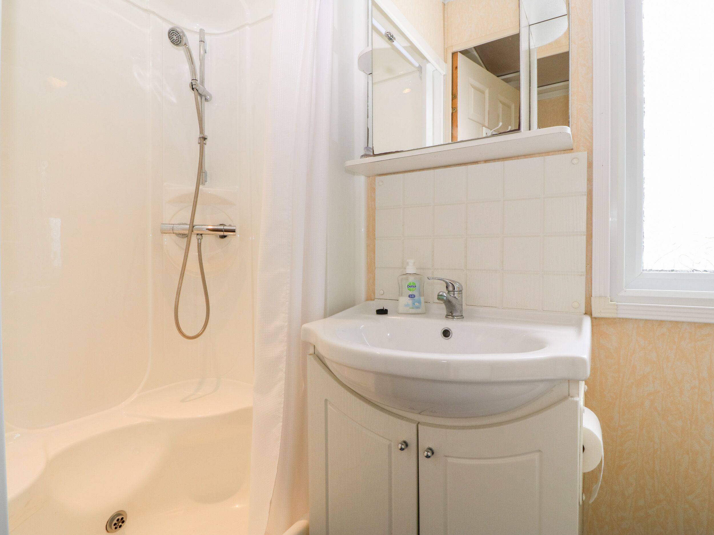 Een badkamer met een bad, een wastafel, een spiegel en een raam.