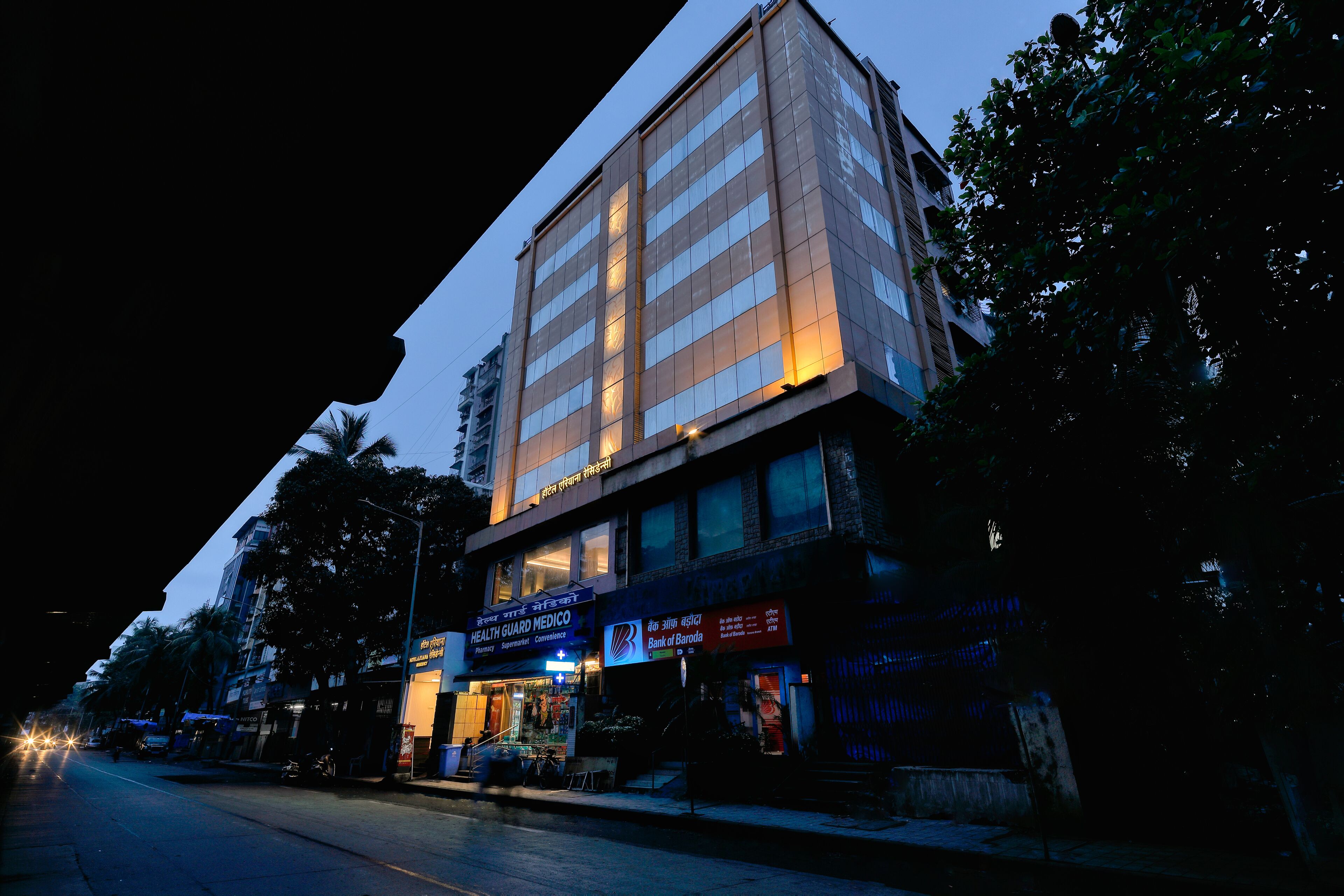 A multi-story building with a ground-level Health Guard Medical facility and a Bank of Baroda branch.
