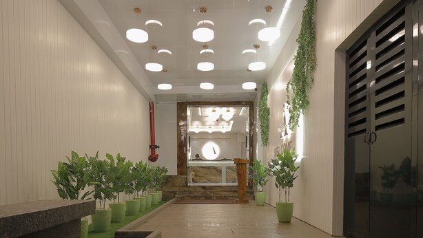 Un moderno vestíbulo de hotel con una escalera central, plantas en macetas y un mostrador de recepción.