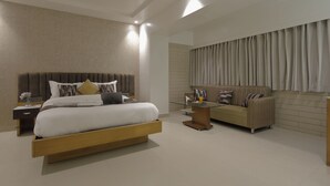Un dormitorio moderno con una cama grande, un sofá, una mesita de noche y una mesa de vidrio.