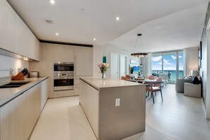 A modern kitchen with built-in appliances, a dining area with a view, and a living space with a large window.