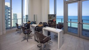 Un espacio de oficina moderno con ventanas amplias, un escritorio, sillas y vista al océano.