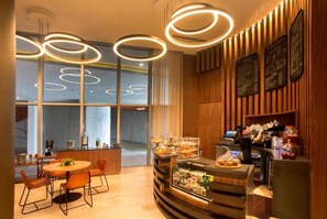 A modern restaurant with a wooden interior, a bar area, and a buffet with various food items.