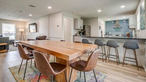 Una cocina moderna con una isla grande, taburetes de bar y un comedor con mesa y sillas de madera.