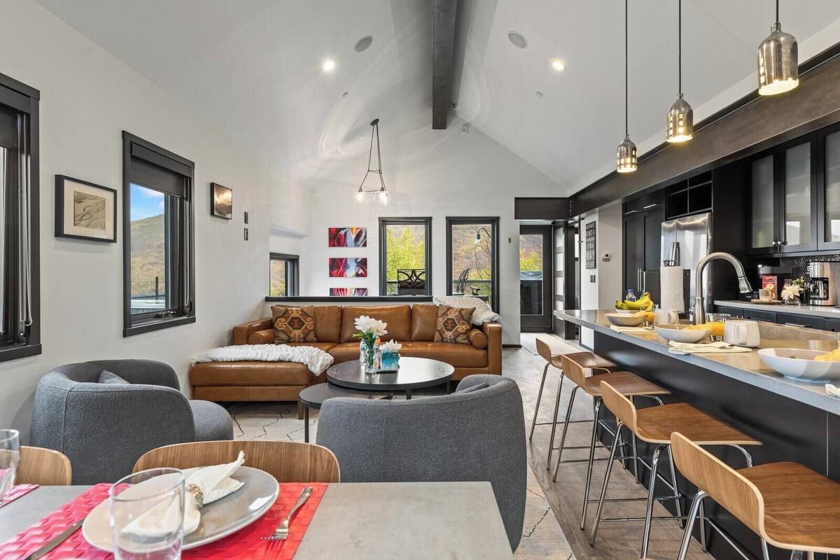 A modern kitchen with a bar area, a dining table with chairs, and a sofa in the living area.