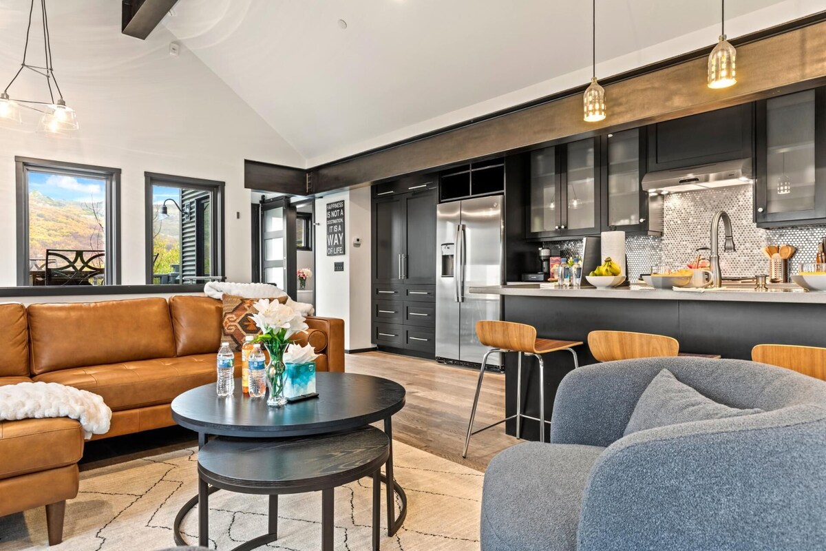A modern living room with a leather sofa, a round coffee table, and a grey armchair.