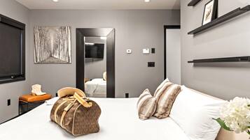 A modern hotel room with a large bed, a bedside table, a mirror, and a wardrobe.