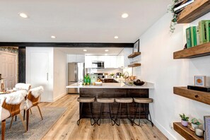 A modern kitchen with a central island, bar stools, and wooden shelves. - Aspen Grove 3 Bedrooms AGC-8 by KBM (Park City)