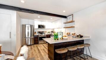 A modern kitchen with a central island, bar stools, and a dog.