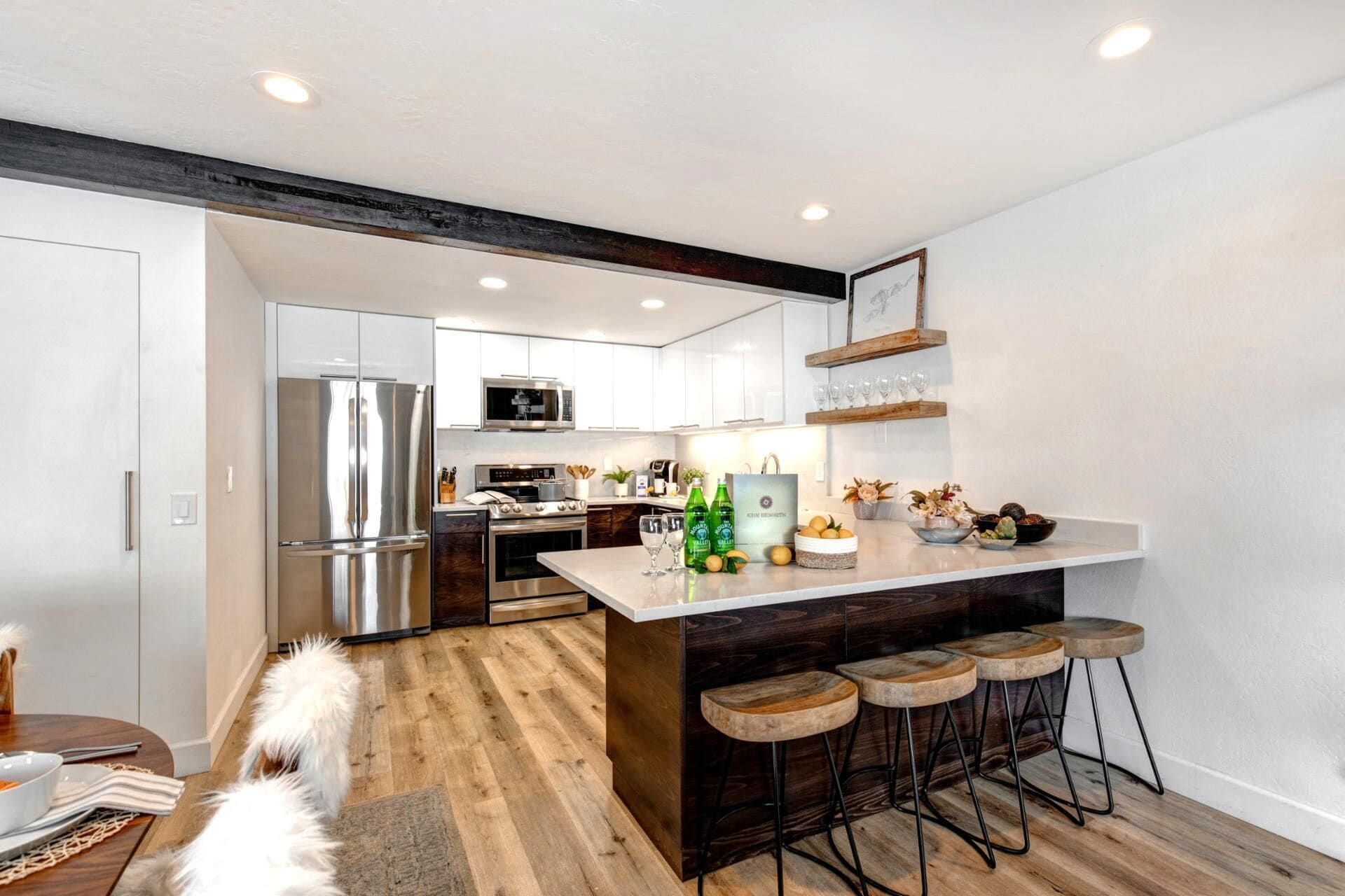 Una cocina moderna con una isla central, taburetes de bar y un perro.