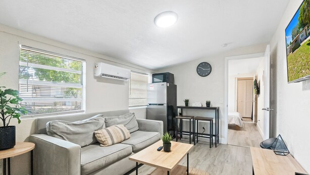 A compact living space with a sofa, a small table, a microwave, and a TV. - Stylish Queen Suite : Near Beach + Shops + Dining (Fort Lauderdale)