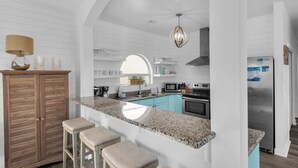 A modern kitchen with a granite countertop, wooden cabinets, and a built-in island with bar stools.