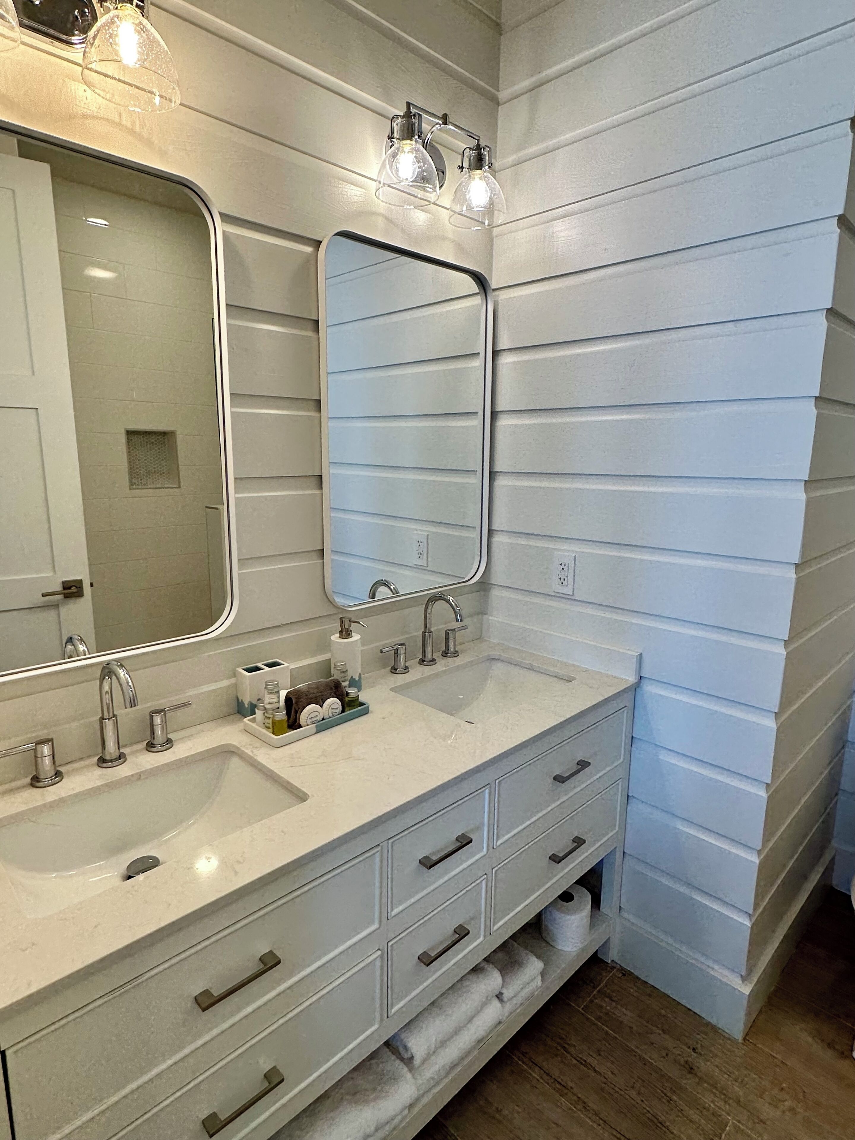 A bathroom with two sinks, a large mirror, and a vanity with drawers.