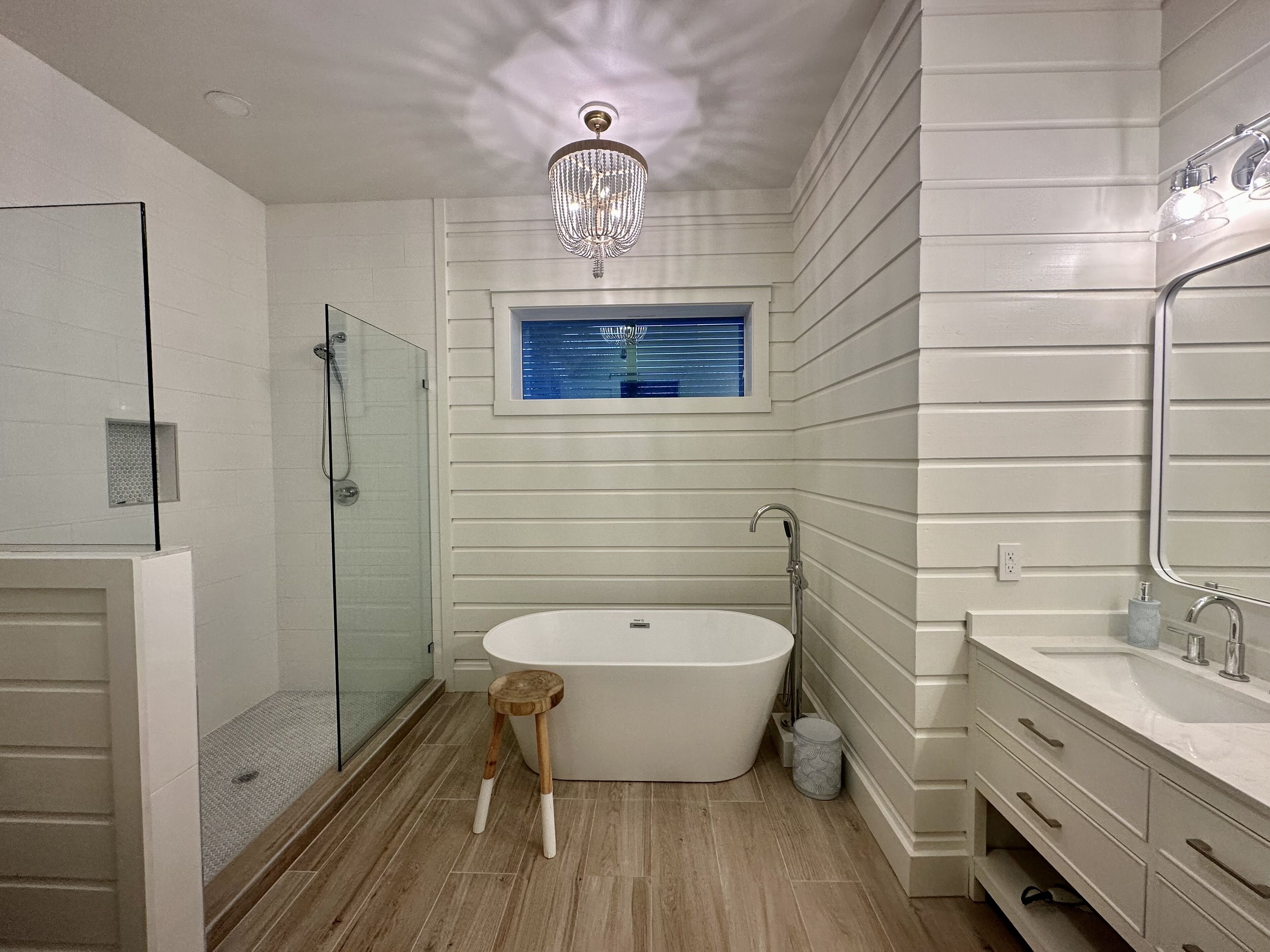 Ein modernes Badezimmer mit einer freistehenden Badewanne, einer Duschkabine aus Glas und einem Waschtisch mit großem Spiegel.