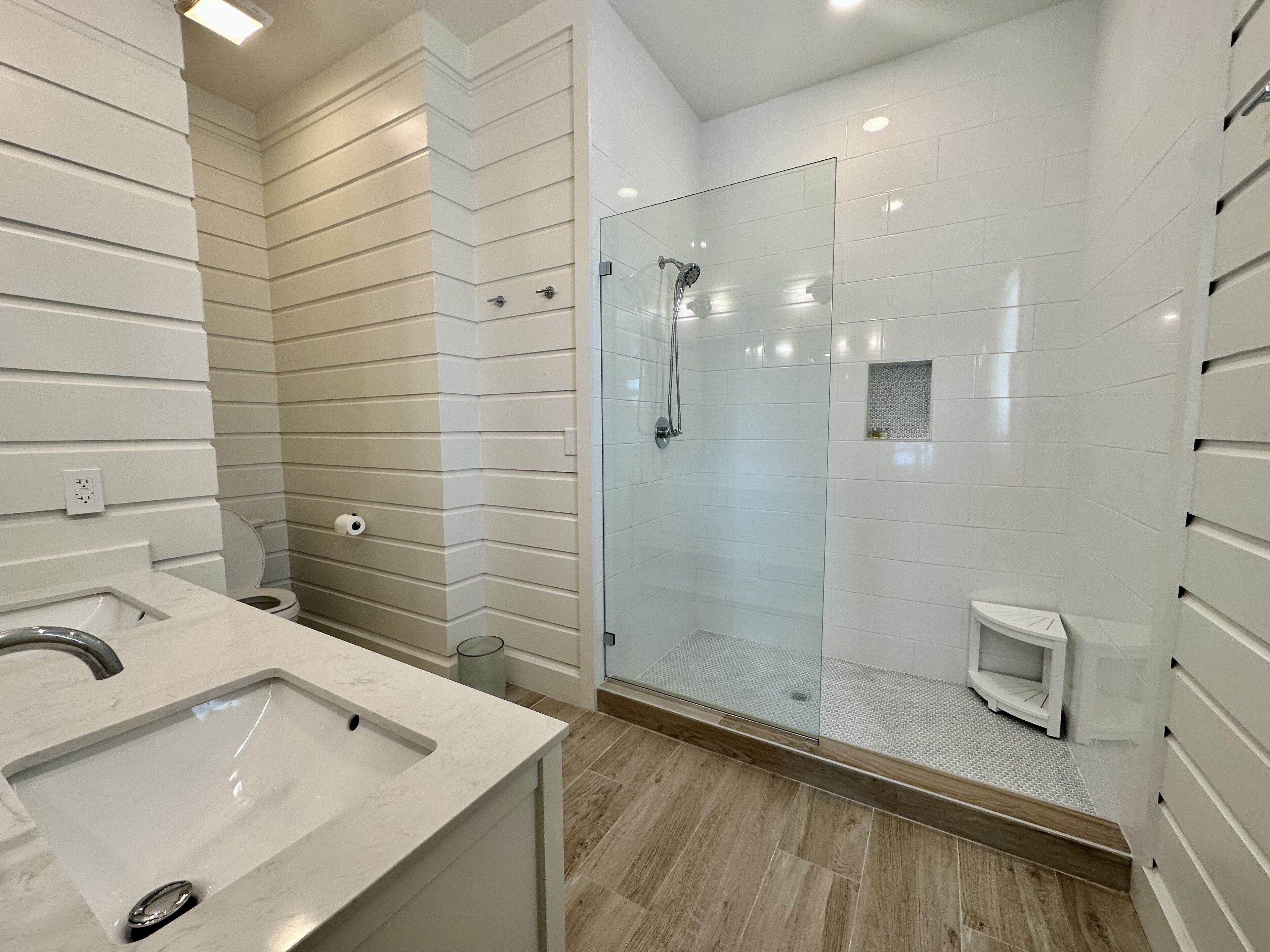 Une salle de bain moderne avec une douche à parois de verre, un lavabo doté d’un plan de travail en marbre et des toilettes.