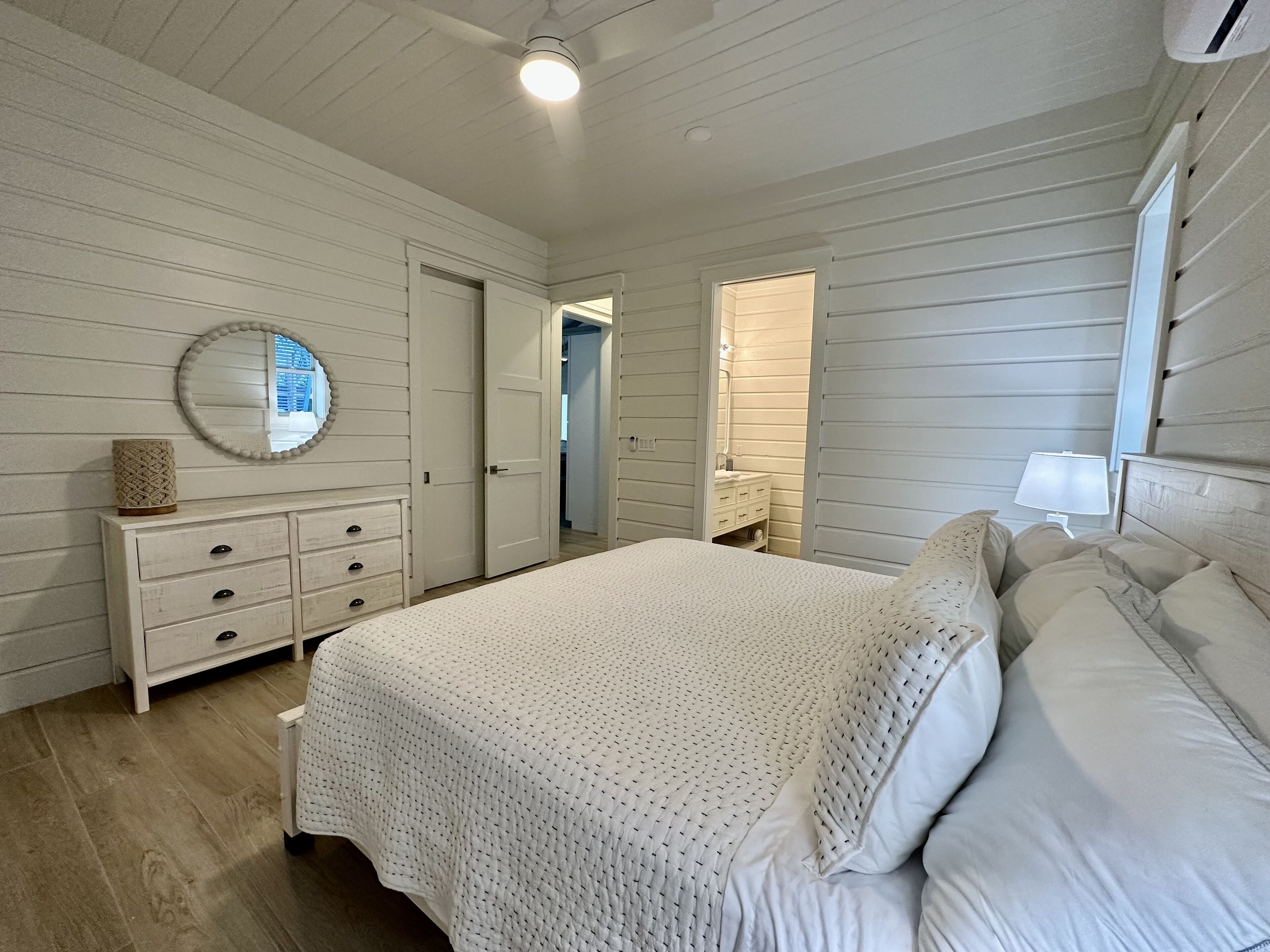 A bedroom with a bed, dresser, and a mirror on the wall.