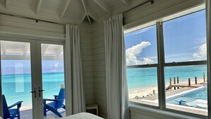A bedroom with a large window overlooking a beach and pool. - Luxury beachfront home, Heated private pool, Five King suites w/ ensuite baths! (Georgetown)