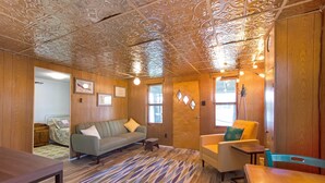 Une pièce chaleureuse avec un plafond décoré de motifs, des murs en bois, un canapé, un fauteuil et une table.