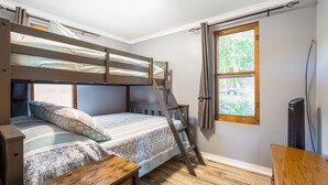 Une chambre avec un lit superposé, une échelle en bois, un bureau et une fenêtre avec des rideaux.